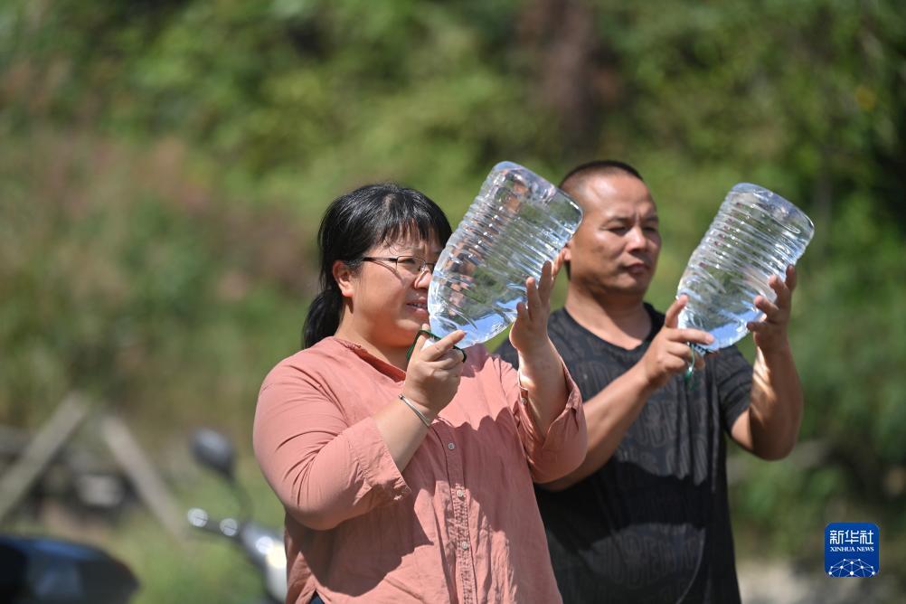 楊寧（左）在查看村民剛剛采集的水樣，為山泉水引水工程做準備（10月8日攝）。新華社記者 黃孝邦 攝